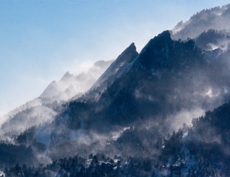Snow billowing off of the Boulder Flatirons